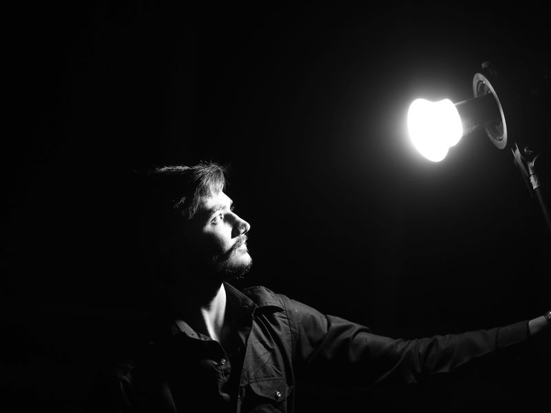 Persona observando una lámpara encendida en un cuarto oscuro